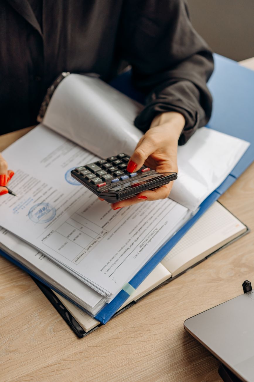 person holding calculator checking on documents